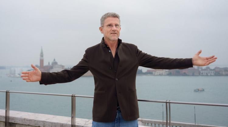 Carlo Ratti stands in front of water with arms outstretched