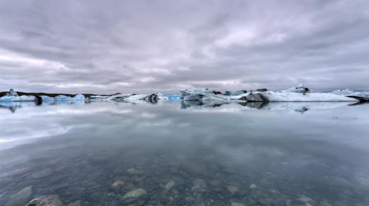 Image of an expanse of water, partially frozen with snow in the background